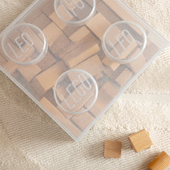 Wooden blocks with a clear plastic container on a textured beige surface