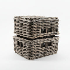 Two gray wicker baskets stacked on a light-colored floor with a tiled wall in the background.