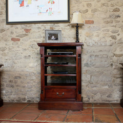 Wooden shelf with a lamp and framed picture against a stone wall.