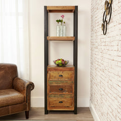 Tall wooden shelf with three drawers against a white brick wall.