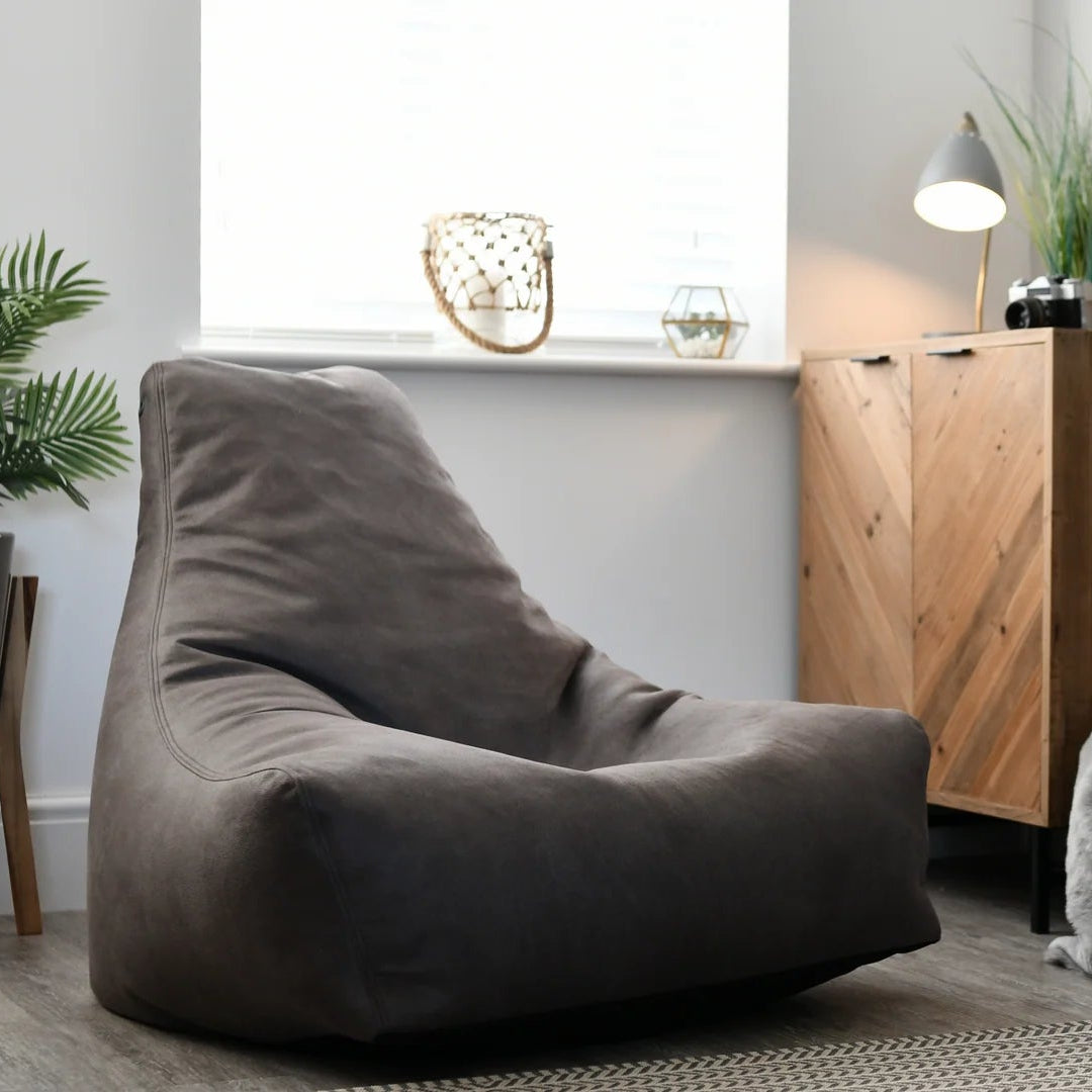 Modern living room with a brown bean bag chair, wooden cabinet, and plants.