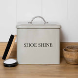Clay coloured  shoe shine container with a black lid on a wooden surface.