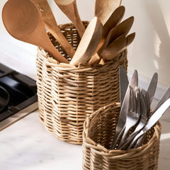 Two wicker baskets filled with wooden and metal utensils on a kitchen counter.