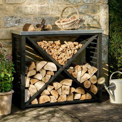 Wooden firewood storage unit against a stone wall with a basket on top.