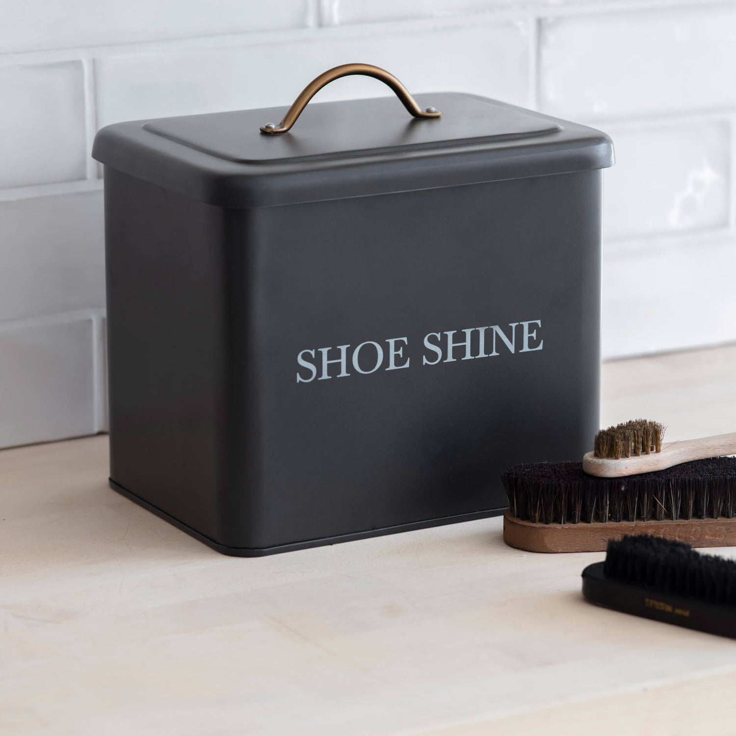 Black shoe shine box with 'SHOE SHINE' text on a white tiled floor.