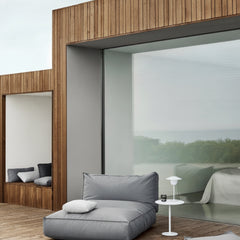 Modern outdoor living space with a gray sofa and wooden walls.