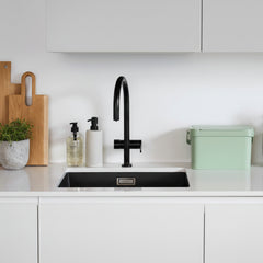 Modern kitchen with black faucet, white countertop, and green decorative items.