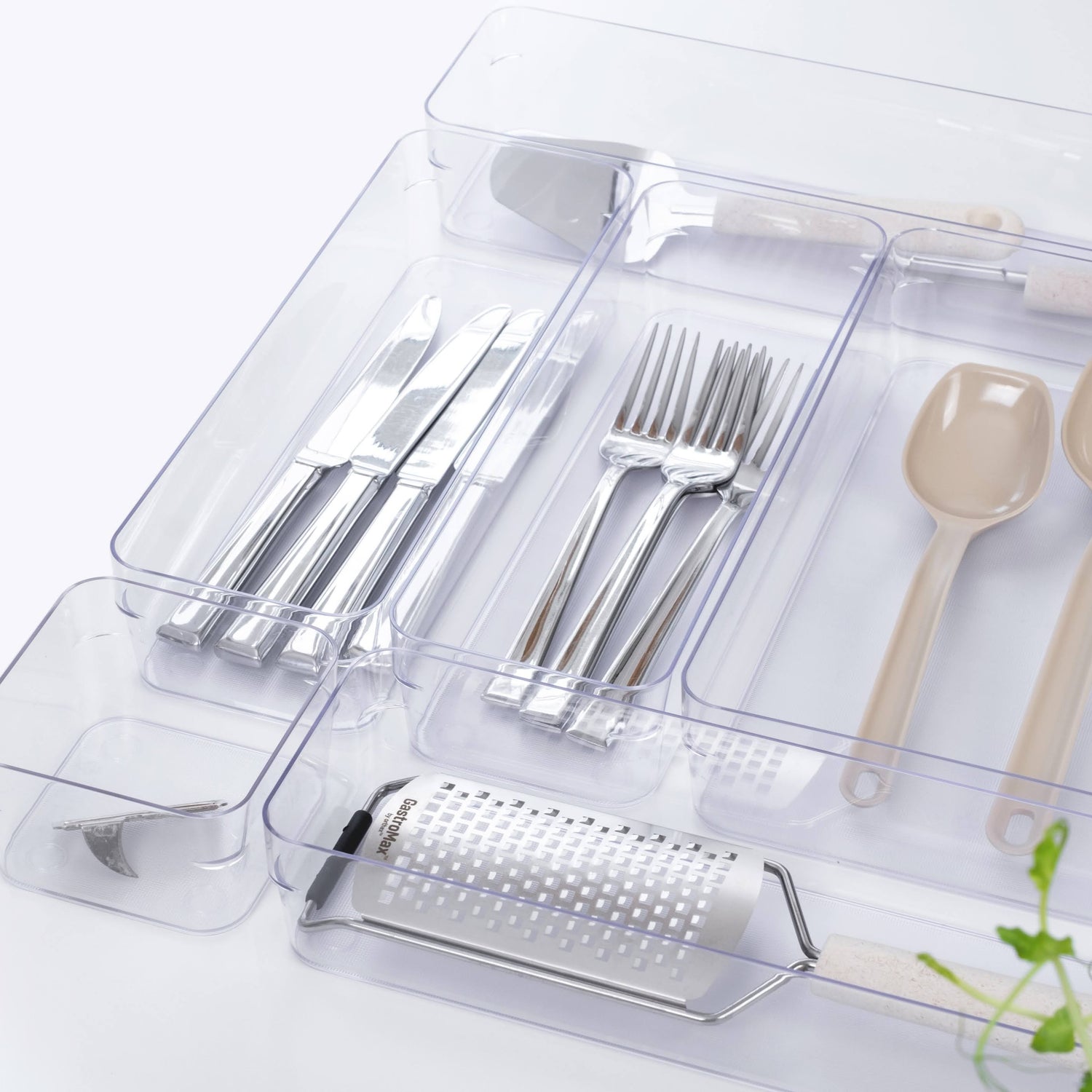 Set of silver cutlery and kitchen tools in a clear plastic organizer on a white background.