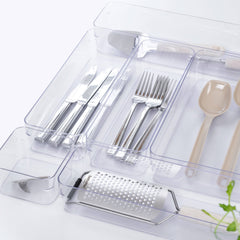 Set of silver cutlery and kitchen tools in a clear plastic organizer on a white background.