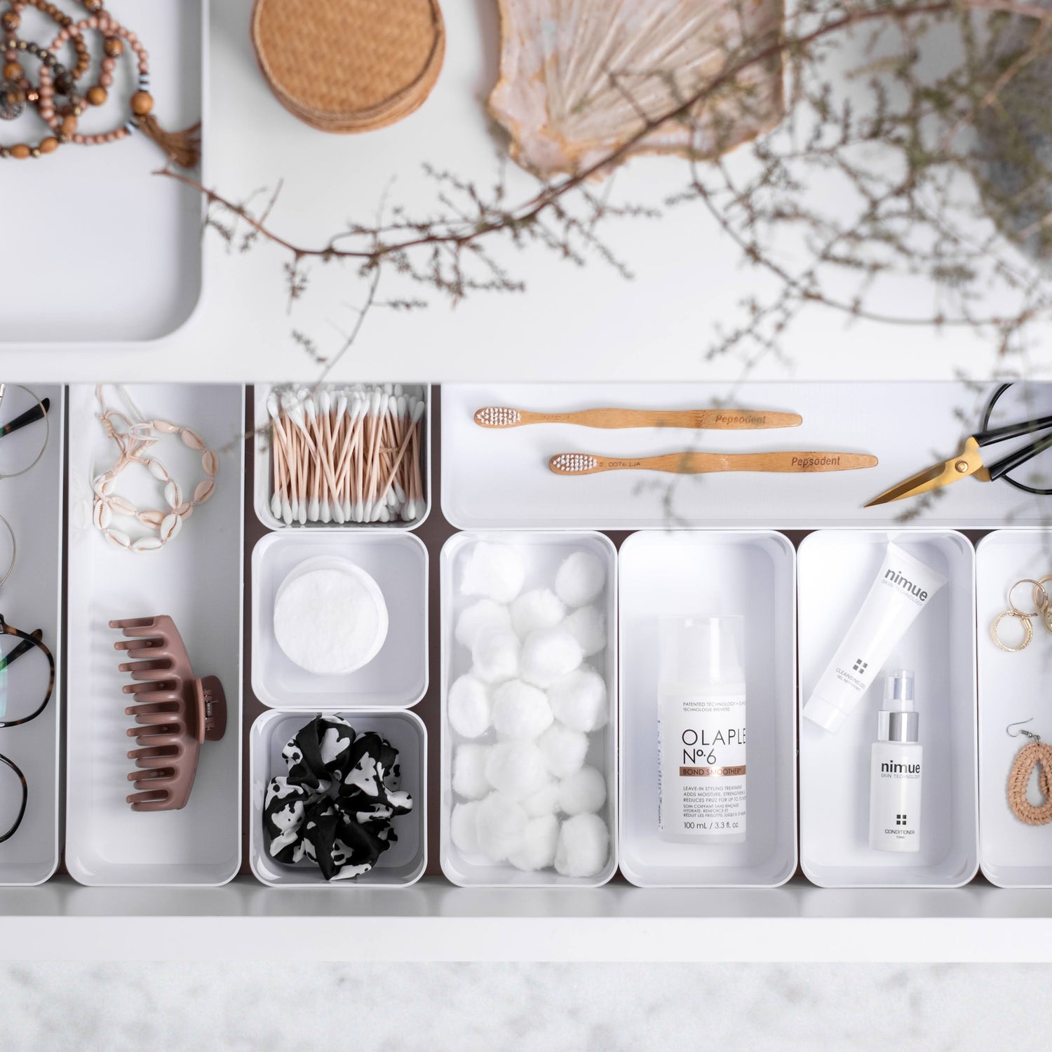Organized drawer with various items including a bottle of Clari, glasses, and other small objects.