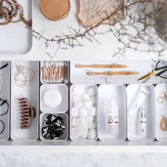 Organized drawer with various items including a bottle of Clari, glasses, and other small objects.