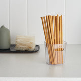 Bamboo straws in a clear container on a white surface with a white background