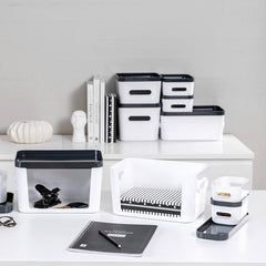 White desk with office supplies including books, containers, and stationery on a neutral background