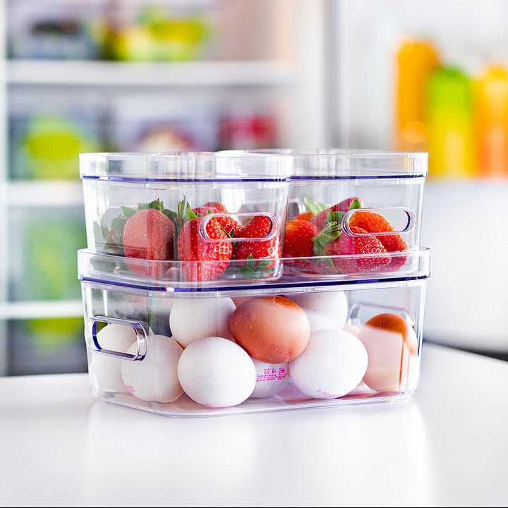 Stackable food storage containers with fruits and eggs in a kitchen setting