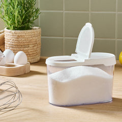 White container with a lid on a kitchen counter, surrounded by eggs, lemons, and a plant.