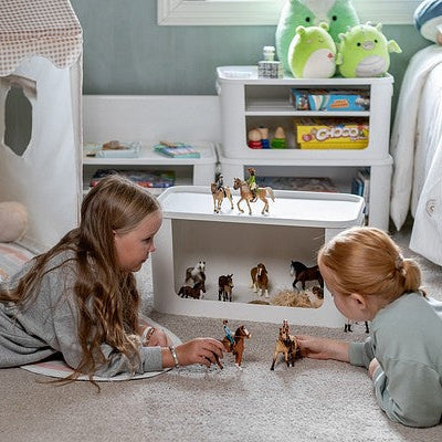Two children playing with toy figures on the floor in a child's bedroom.