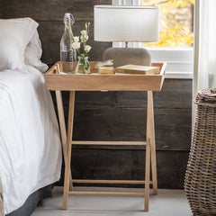 Wooden nightstand with bottles and a lamp next to a bed in a bedroom.