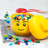 Yellow container shaped like a face with colorful building blocks and a jump rope on a light background