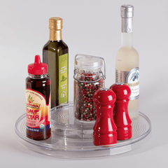 Collection of condiments including a bottle of agave nectar, olive oil, a pepper grinder, and a salt shaker on a clear tray.