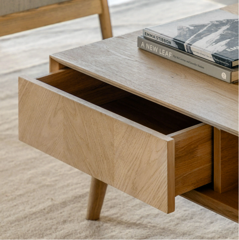 Wooden desk with an open drawer and books on a light background
