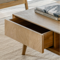 Wooden desk with an open drawer and books on a light background